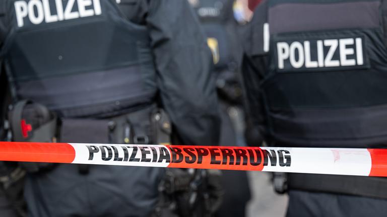 Polizisten hinter einem Absperrband (Mottobild)