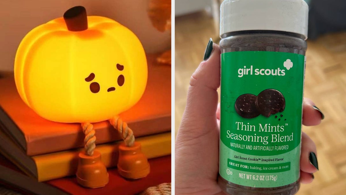 A small pumpkin-shaped light with a sad face and rope legs sits on books. Next to it, a hand holds a Girl Scouts Thin Mints Seasoning Blend bottle