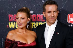 Blake Lively and Ryan Reynolds pose on the red carpet for the "Deadpool & Wolverine" event. Blake wears an off-shoulder dress, Ryan in a classic suit
