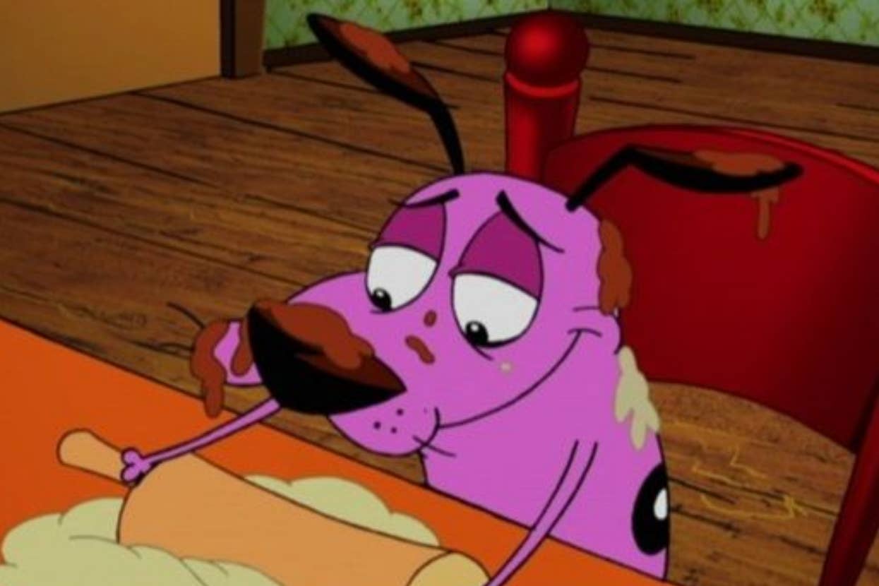 Courage the Cowardly Dog covered in brown spots is using a rolling pin at a wooden table. The scene is set indoors