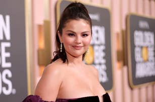 Selena Gomez on the red carpet at the Golden Globe Awards, wearing an elegant off-the-shoulder dress with drop earrings and a high ponytail