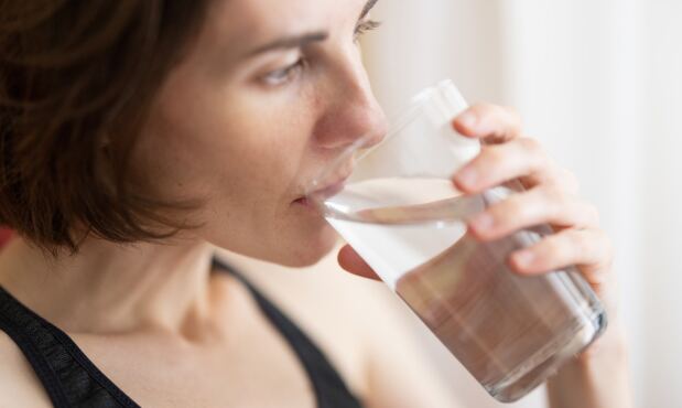 Una mujer tomando un vaso de agua.