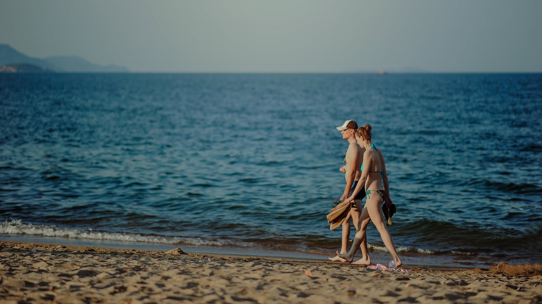 Photo of man and woman walking on seashore