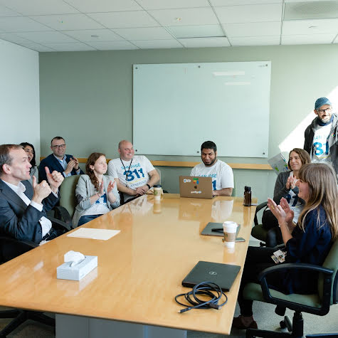 A large group of people in a conference room smiling and clapping.