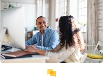 Zwei Personen vor einem großen Monitor, die Berufliches besprechen.