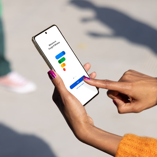 A person's hands hold a Pixel phone. The screen is angled away and shows the Google Fi Wireless login page.