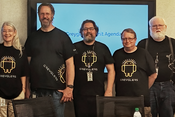 Cinco empleados de Google parados juntos sonríen usando camisetas que dicen "Greyglers"