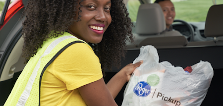 A woman loading Kroger bags into a car