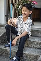 Hayden Zaller, smiling, sitting on stairs holding blue cane