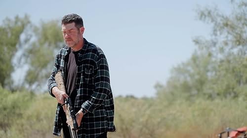 MAC HOLLIS fires his rifle for some sniper target practice on some trees.