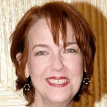 a close up of a woman 's face with red hair and earrings .