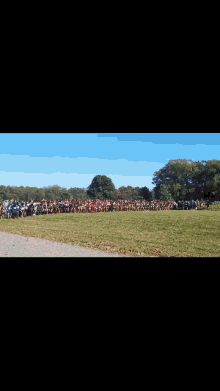 a group of runners are running on a grassy field . one of the runners has the number 1955 on his jersey .