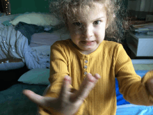 a little girl wearing a yellow shirt with buttons on the front