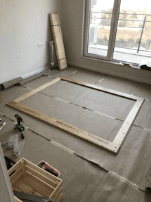 a wooden frame is being built in a room with a drill on the floor