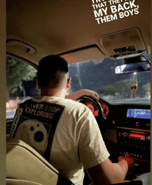 a man wearing a shirt that says " ever stop exploring " driving a car