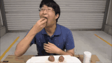 a man in a blue shirt is eating something from a white plate