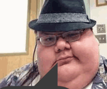 a fat man wearing a hat and glasses looks at the camera