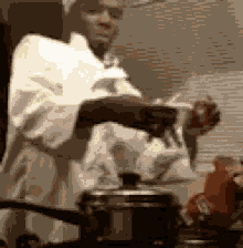 a man in a chef 's coat is cooking in a pot .