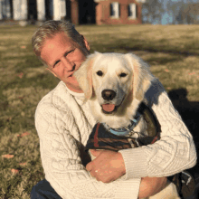 a man in a white sweater is holding a dog