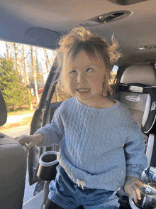 a little girl sits in a car seat that says graco