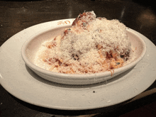 a white plate with a bowl of spaghetti and meatballs on top