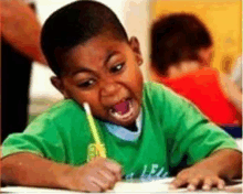 a young boy is making a funny face while writing in a notebook