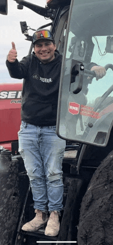 a man giving a thumbs up while standing in front of a tractor