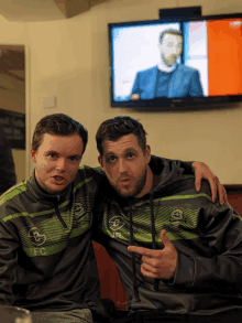 two men are posing for a picture with one wearing a sweatshirt that says fc