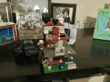 a lego house sits on a table next to a picture frame that says home