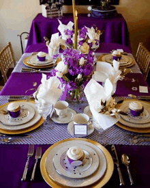 a table set for a party with purple and gold plates and silverware