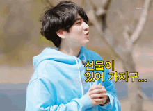 a young man in a blue hoodie with korean writing on it