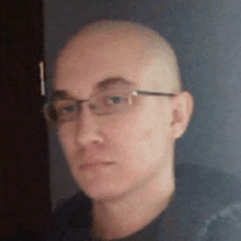 a close up of a bald man wearing glasses and a black shirt .