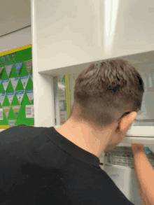 a man in a black shirt is cleaning a refrigerator door