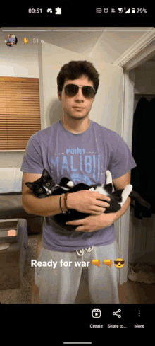 a man holding a cat wearing a purple shirt that says point malibu