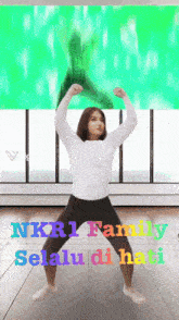 a woman is dancing in front of a green screen that says nkr1 family