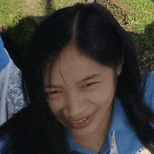 a close up of a girl making a funny face while laying in the grass .