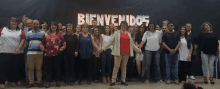 a large group of people are posing in front of a sign that says bienvenidos