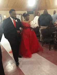 a man in a suit is walking a woman in a red dress down the aisle .