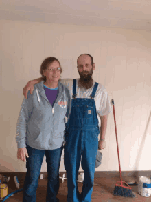 a man wearing overalls stands next to a woman wearing a grey sweatshirt that says ' i love you '