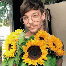 a man wearing glasses holds a bunch of sunflowers with the words little dandelion lou on the bottom