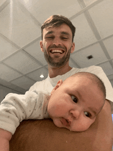 a man holds a baby in his arms and smiles