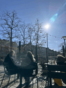 two women sit at a table in front of a tree