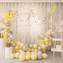 a room filled with lots of yellow and gray balloons and a balloon arch .