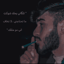 a man with a beard is smoking a cigarette with arabic writing on it