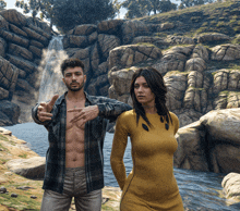 a man and a woman are standing next to a waterfall