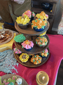 a wooden tray filled with cupcakes decorated with flowers