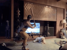 a man in a dodgers hat is swinging a bat in a living room