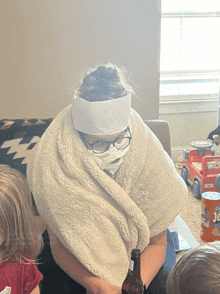 a woman wrapped in a blanket with a bandage on her head holds a bottle