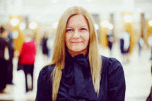 a woman with long blonde hair wearing a black shirt with a bow