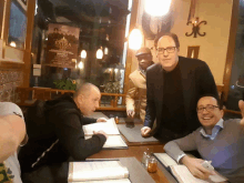 a group of men sit at a table in front of a sign that says " extra "